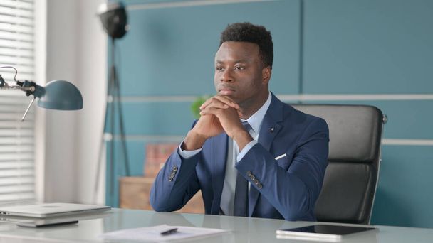 オフィスに座っている間に考えるアフリカのビジネスマン - 写真・画像