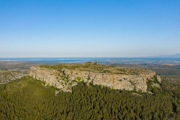 Cette photo de paysage a été prise en Europe, en France, en Occitanie, dans les Pyrénées orientales, en été. Nous voyons le Château d'Opoul Perillos entouré de forêts sur le flanc de la falaise, sous le soleil. - Photo, image