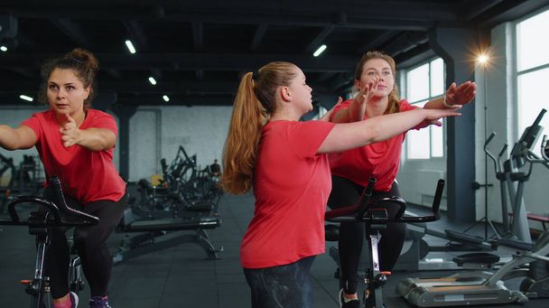 Skupina dívek provádí aerobní trénink kardio rutina na cyklistických simulátorech, cyklistický trénink - Fotografie, Obrázek