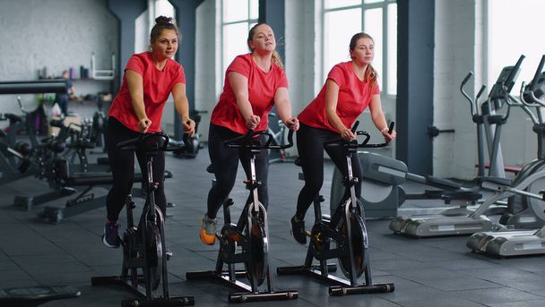 Groupe de filles effectue entraînement aérobie entraînement cardio routine sur simulateurs de vélo, cycle d'entraînement - Photo, image