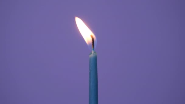 Blowing out one cake candle burning on a purple background. Close up on burning blue cake candle. Full HD resolution slow motion happy birthday or anniversary video banner. - Footage, Video