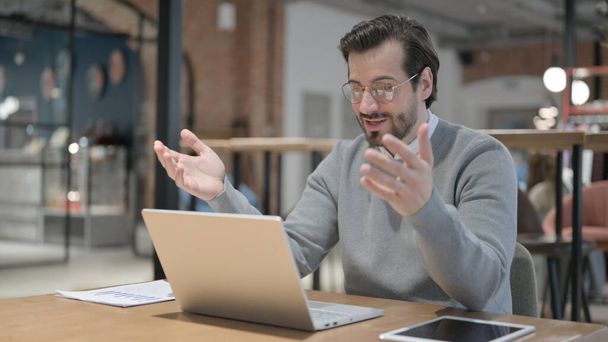 Fiatal férfi beszél videohívás Laptop az irodában - Fotó, kép