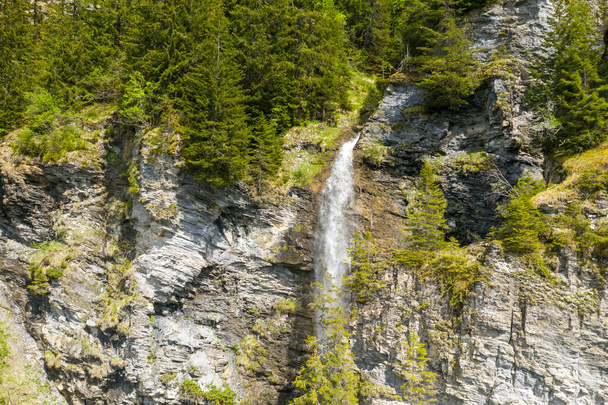 To zdjęcie krajobrazowe zostało zrobione w Europie, we Francji, w kierunku Beaufort, w Alpach, latem. Widzimy wodospad na skraju jeziora Saint Guerin, pod Słońcem. - Zdjęcie, obraz