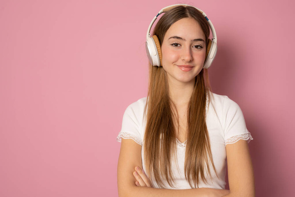 Close up portrait of smiling young woman wearing headphones over pink background. - Фото, изображение