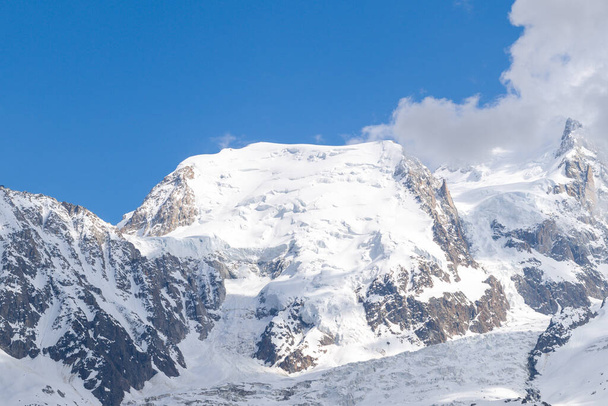 Cette photo de paysage a été prise en Europe, en France, dans les Alpes, vers Chamonix, en été. On voit le gros plan sur le Mont Blanc du Tacul entouré de nuages dans le massif du Mont Blanc, sous le soleil. - Photo, image