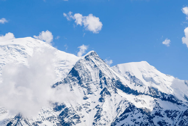 Deze landschapsfoto is genomen in Europa, in Frankrijk, in de Alpen, richting Chamonix, in de zomer. We zien de wolken boven de Mont Blanc, de Aiguille de Bionnassay en de Aiguille du Gouter, onder de zon. - Foto, afbeelding