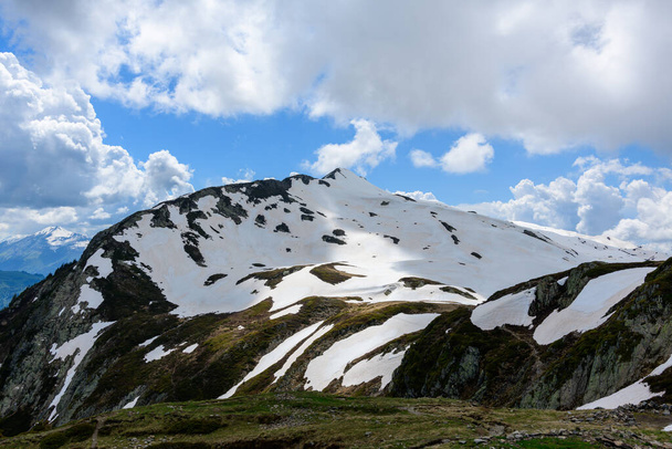 Αυτή η φωτογραφία τοπίου τραβήχτηκε στην Ευρώπη, στη Γαλλία, στις Άλπεις, προς το Chamonix, το καλοκαίρι. Βλέπουμε το χιονισμένο lAiguillette des Houches κάτω από τα σύννεφα στο βουνό Mont Blanc, κάτω από τον ήλιο. - Φωτογραφία, εικόνα