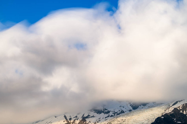 Tato fotografie krajiny byla pořízena v Evropě, ve Francii, v Alpách, směrem na Chamonix, v létě. Vidíme mraky pohybující se kolem Aiguille du Midi v masivu Mont Blanc, pod sluncem. - Fotografie, Obrázek