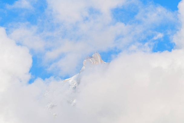 Tato fotografie krajiny byla pořízena v Evropě, ve Francii, v Alpách, směrem na Chamonix, v létě. Vidíme, že mraky ukrývají Aiguille du Midi v masivu Mont Blanc, pod sluncem. - Fotografie, Obrázek
