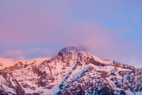 This landscape photo was taken in Europe, in France, in the Alps, towards Chamonix, in summer. We see Mont Blanc and the Aiguille du Gouter surrounded by pink clouds. - 写真・画像