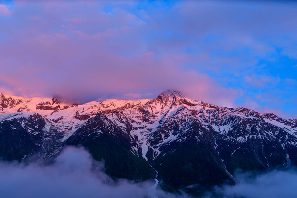 Tato fotografie krajiny byla pořízena v Evropě, ve Francii, v Alpách, směrem na Chamonix, v létě. Vidíme Mont Blanc Massif obklopený narůžovělými mraky. - Fotografie, Obrázek