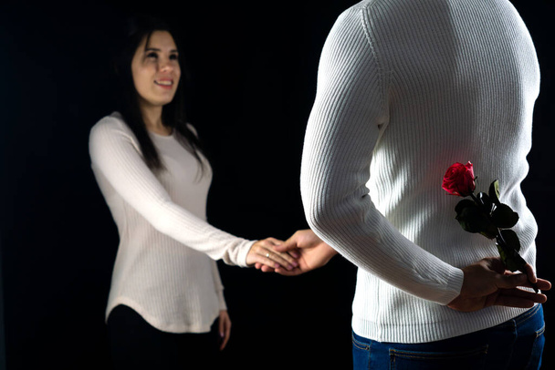 Hombre irreconocible escondiendo una rosa mientras sostiene la mano de su esposa antes de darle una sorpresa. - Foto, imagen