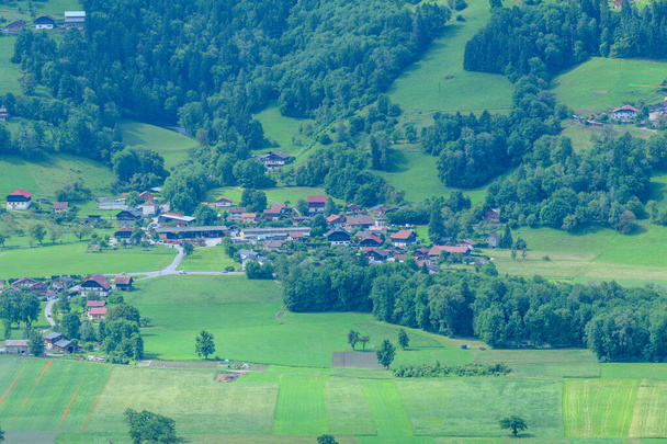 Эта пейзажная фотография была сделана в Европе, во Франции, в Альпах, в Шамони, летом. Мы видим деревню в середине лесов к Пасси в массиве Монблан, под солнцем. - Фото, изображение