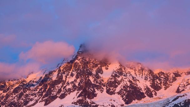 Tato fotografie krajiny byla pořízena v Evropě, ve Francii, v Alpách, směrem na Chamonix, v létě. Můžeme vidět růžové mraky kolem Aiguille du Midi v Mont Blanc masivu, pod sluncem. - Fotografie, Obrázek