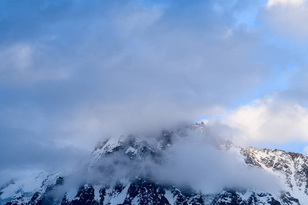 Tato fotografie krajiny byla pořízena v Evropě, ve Francii, v Alpách, směrem na Chamonix, v létě. Vidíme Aiguille du midi pod mraky v masivu Mont Blanc, pod sluncem. - Fotografie, Obrázek