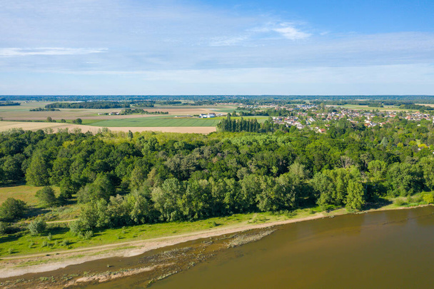 Αυτή η φωτογραφία τοπίου τραβήχτηκε στην Ευρώπη, στη Γαλλία, στην περιοχή του Κέντρου, στο Loiret, το καλοκαίρι. Μπορούμε να δούμε το πράσινο τοπίο προς την πόλη του Sully sur Loire, κάτω από τον ήλιο. - Φωτογραφία, εικόνα