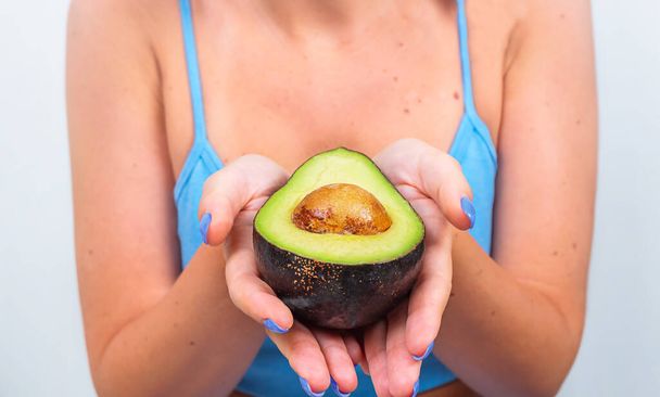Young woman carefully holds half an avocado in her hands - Photo, Image