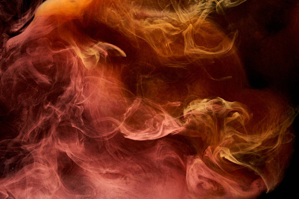 Orange smoke on black ink background, colorful fog, abstract swirling ocean sea, acrylic paint pigment underwater - Photo, Image