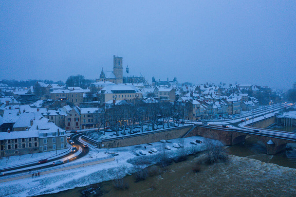 This landscape photo was taken in Europe, France, Burgundy, Nievre, in Winter. We see the city of Nevers under the snow, under the clouds. - Photo, Image