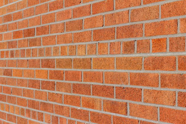 Arrière-plan abstrait plein cadre d'un mur de briques vintage grunge au motif de briques de liaison commun, avec des briques de différentes nuances d'orange et de rouge, ayant un scintillement subtil dans sa patine. - Photo, image