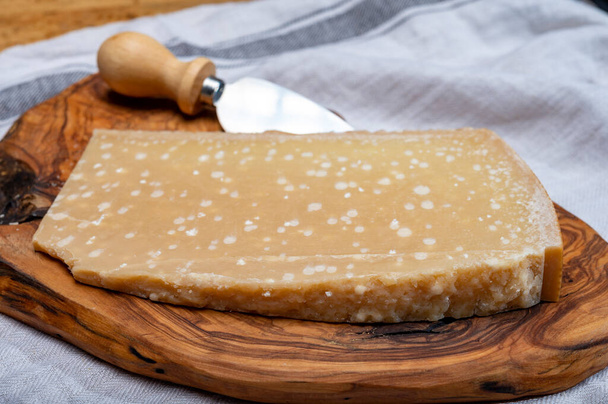 72 months very old Italian parmigiano-reggiano parmesan cheese from Parma has amber color, dry, extremely grainy and crumbly with very intense taste, close up - Foto, Imagen