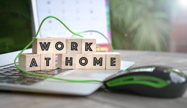 Work at home, word written on wood cubes on top of computer keyboard. - Фото, изображение