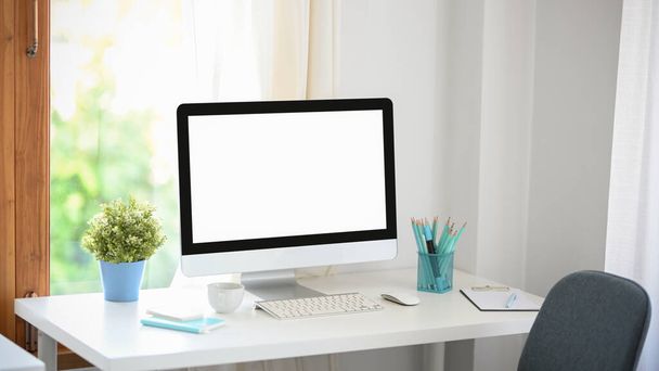 Un espace de travail moderne minimaliste lumineux avec ordinateur de bureau PC maquette écran blanc et fournitures de bureau sur la table. - Photo, image