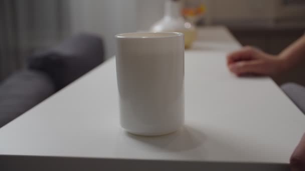 Unrecognizable female hand taking white mug away from shot indoors - Materiał filmowy, wideo