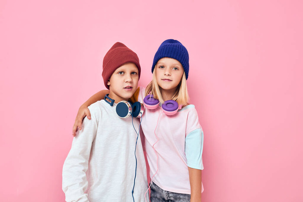 boy and girl in hats headphones hug pink background - Foto, Bild