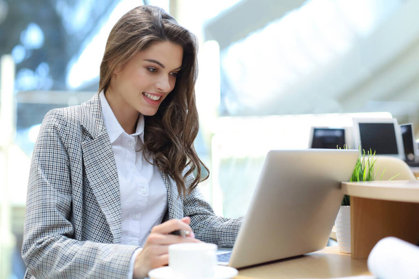 Portrait of a young brunette business woman using laptop at office. - 写真・画像