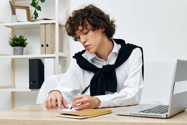 подросток на белом диване перед ноутбуком, изучающий технологию Lifestyle - Фото, изображение