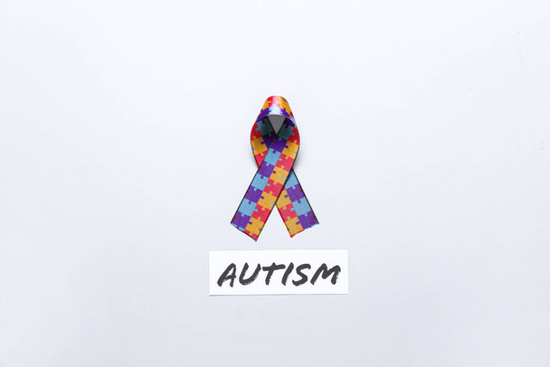 Awareness ribbon with word AUTISM on light background - Photo, Image