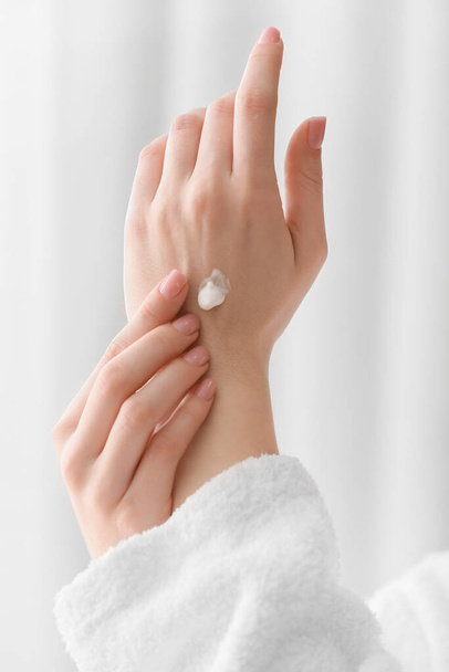 jonge vrouw het aanbrengen van cosmetische crème op haar handen thuis - Foto, afbeelding