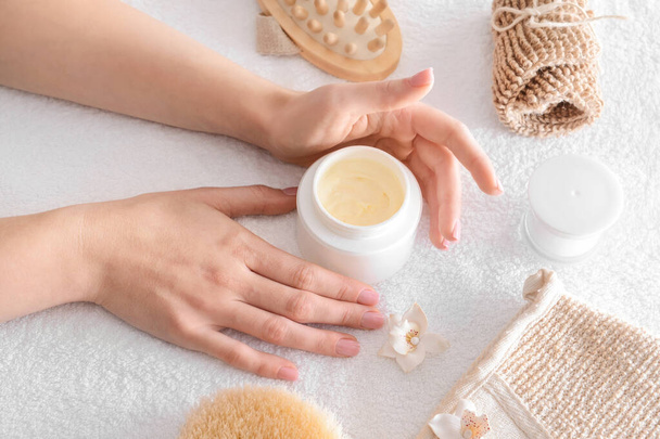Γυναικεία χέρια με καλλυντική κρέμα και προϊόντα μπάνιου στην πετσέτα - Φωτογραφία, εικόνα