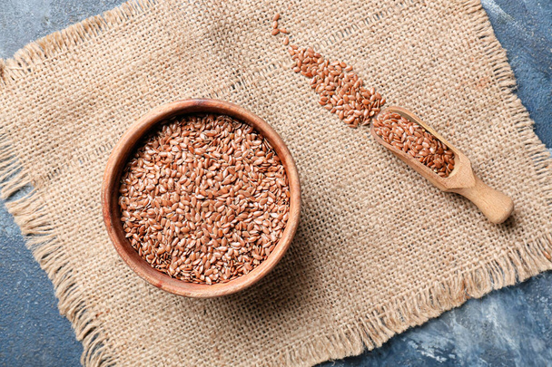 Bowl and scoop with flax seeds on color background - Foto, Bild