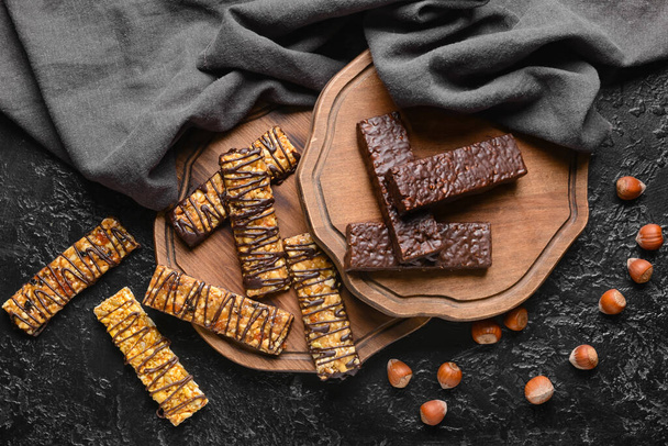 Boards with tasty chocolate nut bars on dark background - Valokuva, kuva