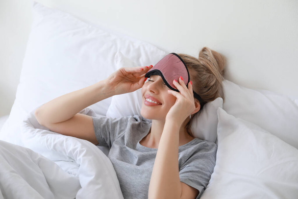 Beautiful young woman taking off sleeping mask in bed - Foto, immagini