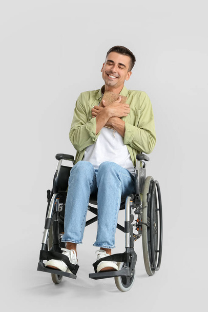 Tekerlekli sandalyedeki genç adam ve arka planı aydınlık. - Fotoğraf, Görsel
