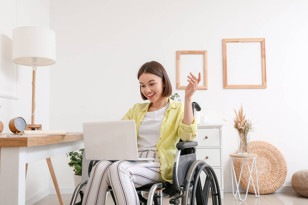 Young woman in wheelchair using laptop at home - Foto, Imagem