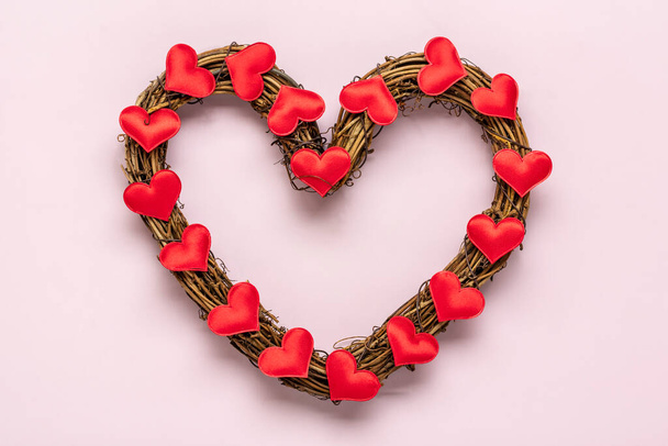 heart shaped rattan wreath decorated with red hearts on pink background Top view Flat lay Holiday card Happy Valentines day, love concept Copy space - Foto, Imagem