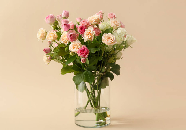 Vase with bouquet of beautiful roses on beige background - Foto, Imagem
