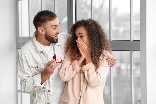 Young man proposing to his girlfriend at home - Fotó, kép
