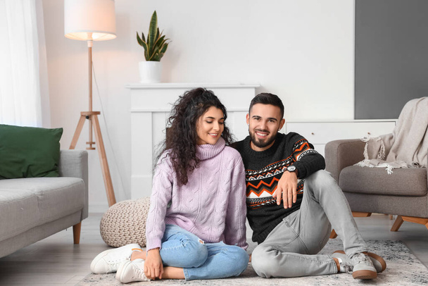 Feliz joven pareja usando suéteres calientes en casa - Foto, imagen