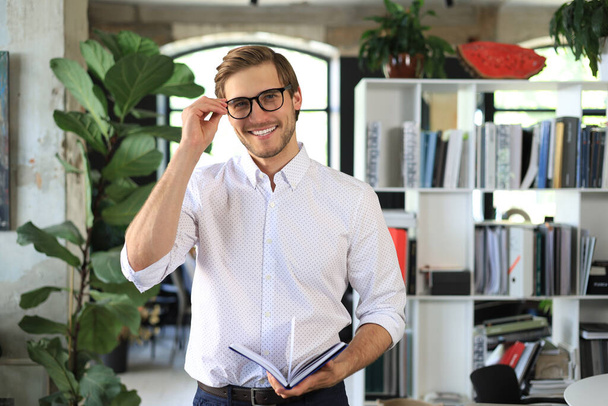 Handsome young businessman standing in modern office - Foto, Imagem