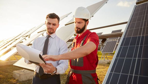 Contractor and manager working in field with solar panels - Foto, afbeelding