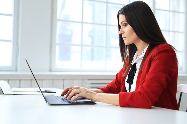 businesswoman in red jacket working in office - Photo, Image