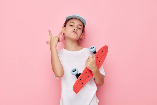 little girl cap in white t-shirt skateboard isolated background - Фото, изображение