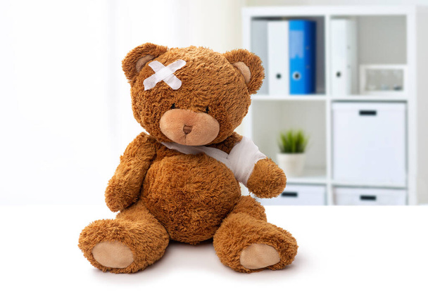teddy bear toy with bandaged paw and patch on head - 写真・画像