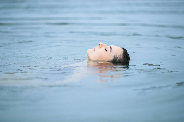 Beautiful woman swimming in lake - 写真・画像
