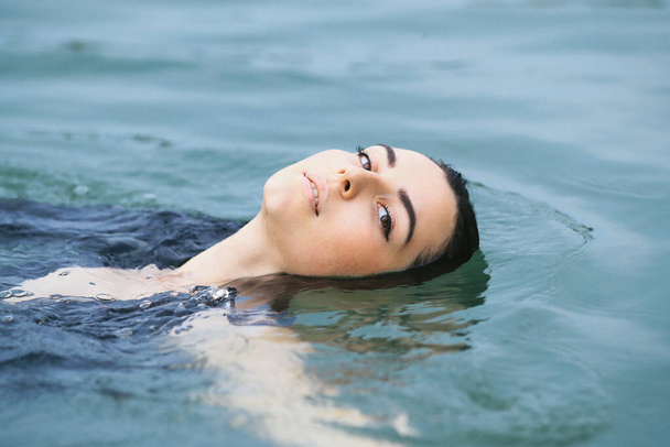 Beautiful woman swimming in lake - 写真・画像